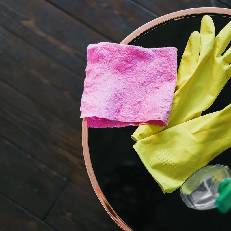 Rubber gloves, a cloth and a spray bottle laid out on a table