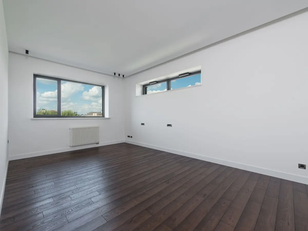 Empty room with a laminate floor and a radiator under the window